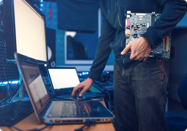 Técnico segurando uma placa-mãe ao lado de notebooks