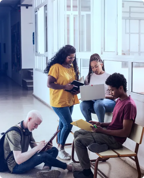 Estudantes com notebook, tablet e cadernos em um corredor