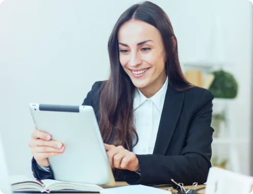 Mulher sorrindo usando um tablet em uma mesa de trabalho